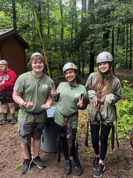 Students preparing to use a zipline in the woods