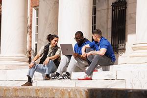 Three male students sitting on the steps of davidson hall