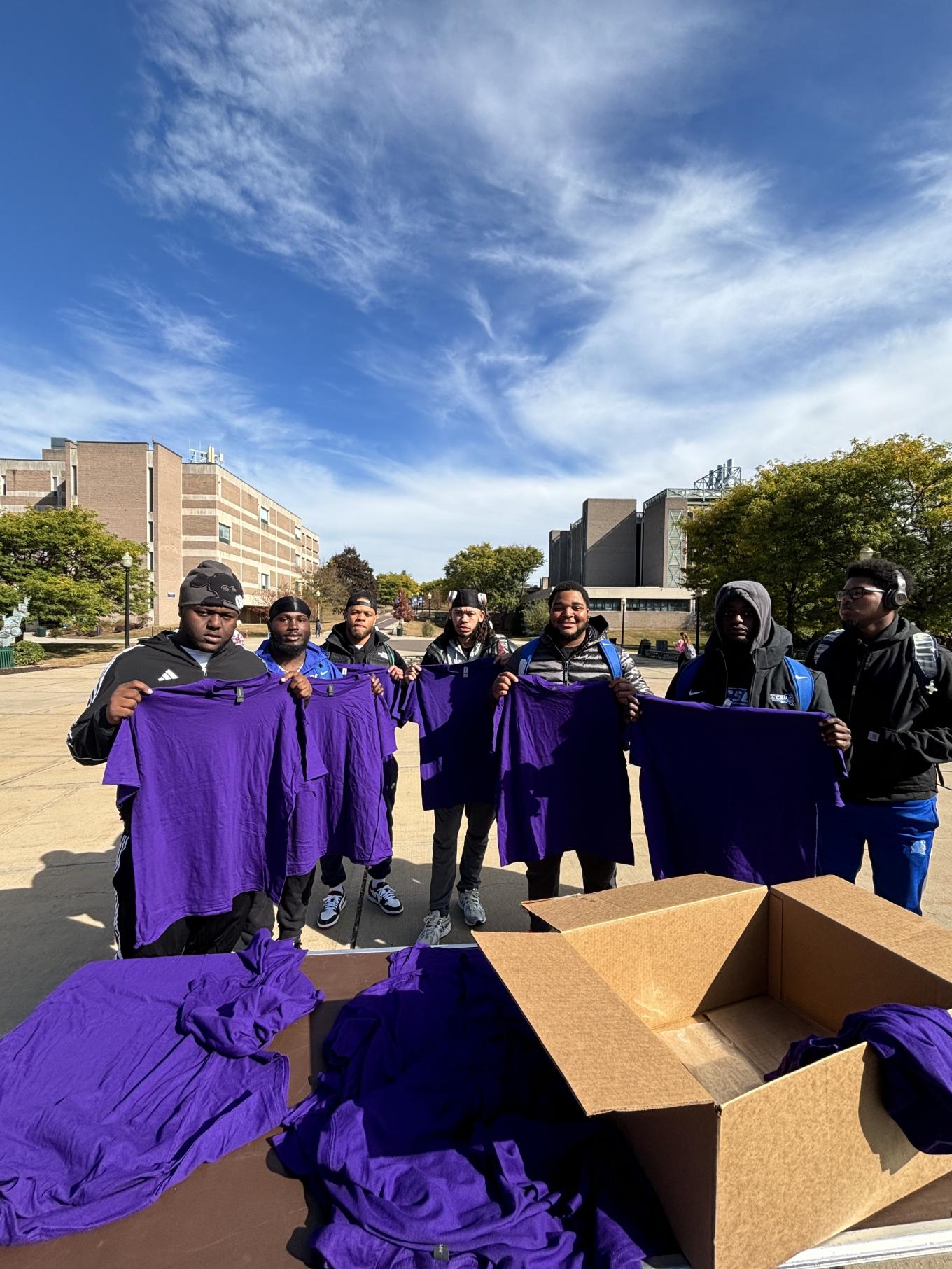 Group holding up purple shirts