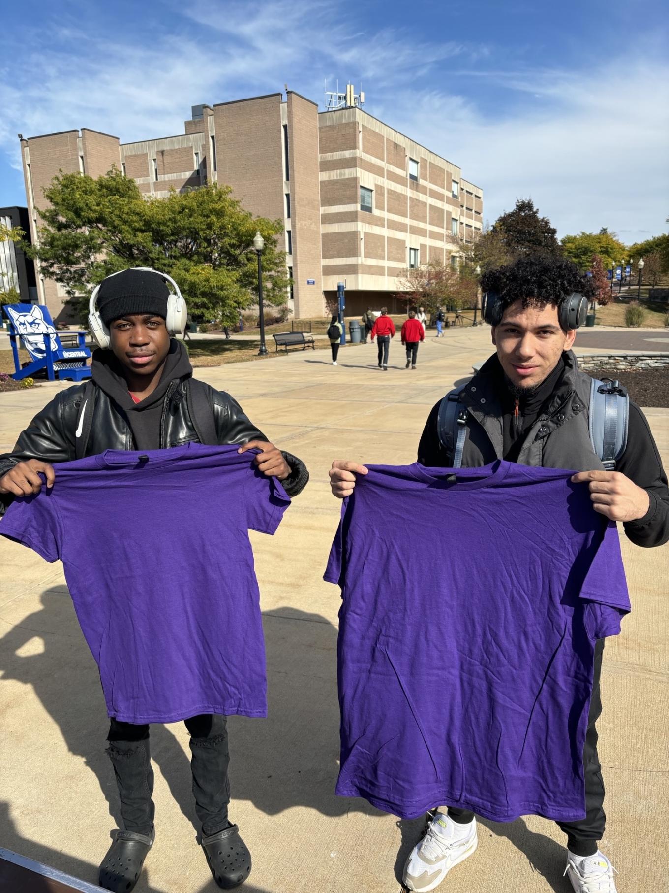 Duo holding up purple shirts